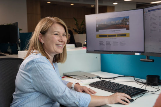 A smiling Powermetric team member at their computer